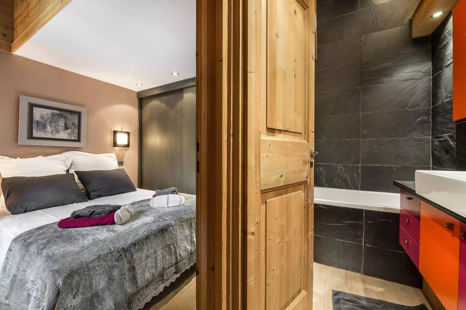 A bedroom with a neatly made bed beside an adjoining bathroom.