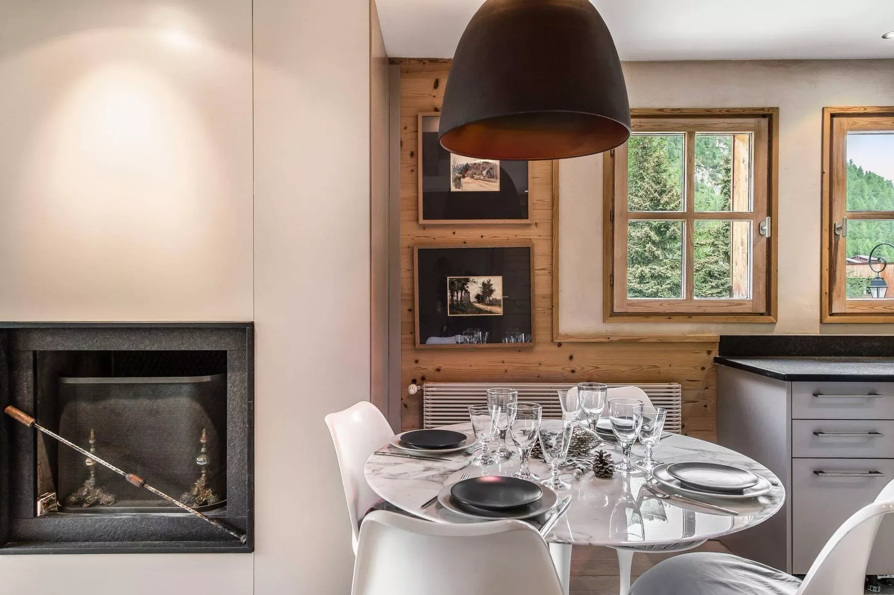 Un comedor con la mesa puesta junto a una chimenea y paredes revestidas de madera.