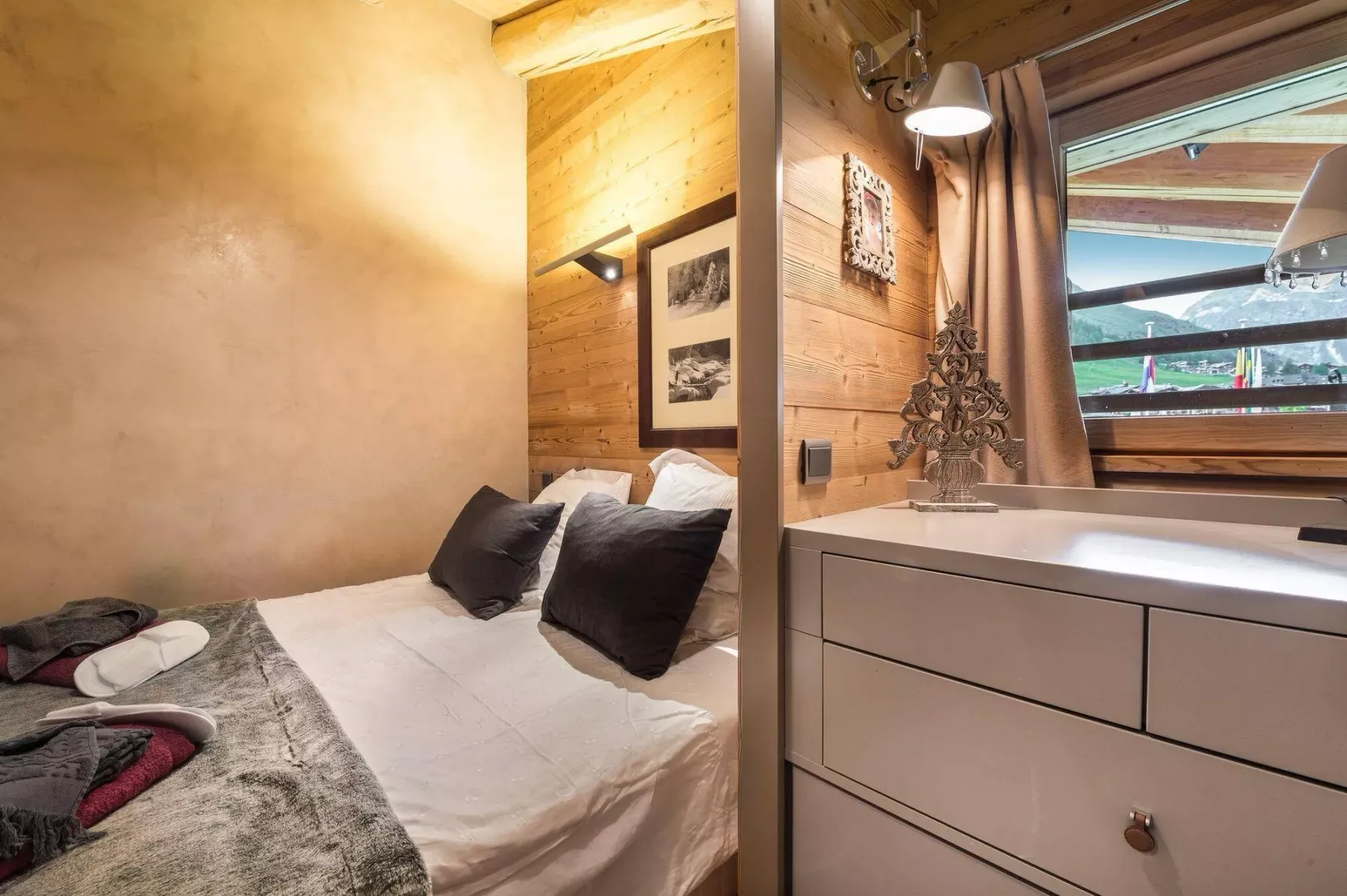 Un dormitorio con una cama junto a una cómoda y una ventana.