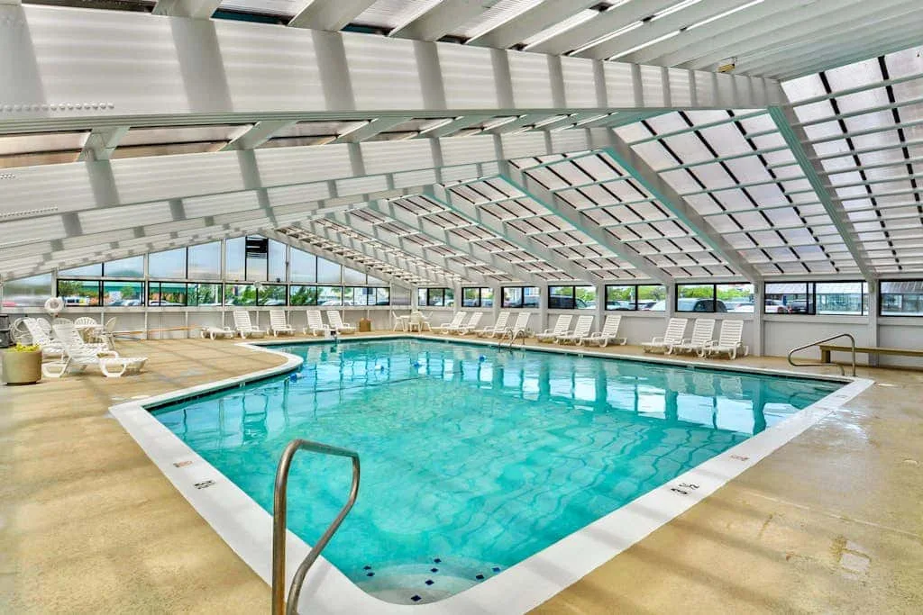 An indoor swimming pool sits beneath a bright, sloped roof.