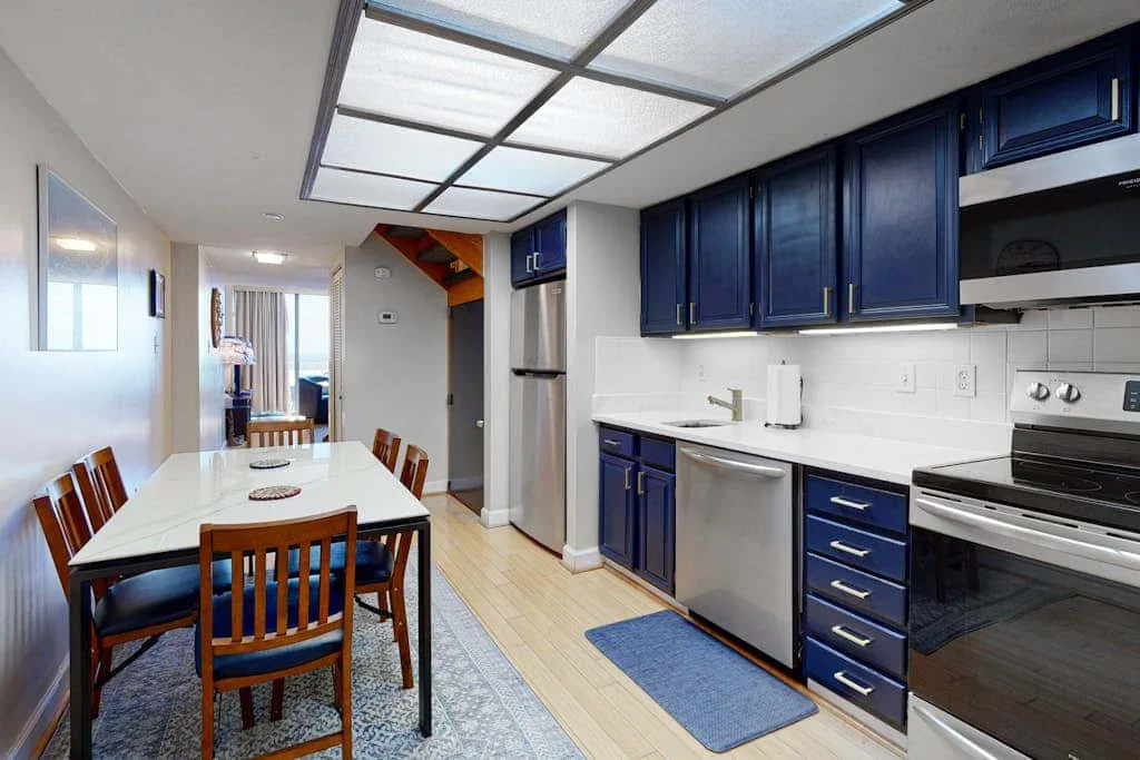 A kitchen and dining area with dark blue cabinets and a table.