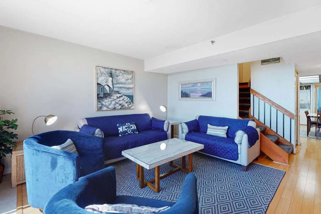A bright living room with blue seating, a coffee table, and framed artwork.