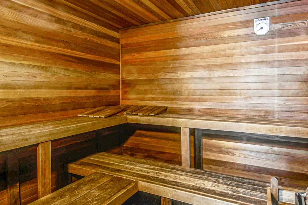A wooden sauna room with tiered benches along the walls.