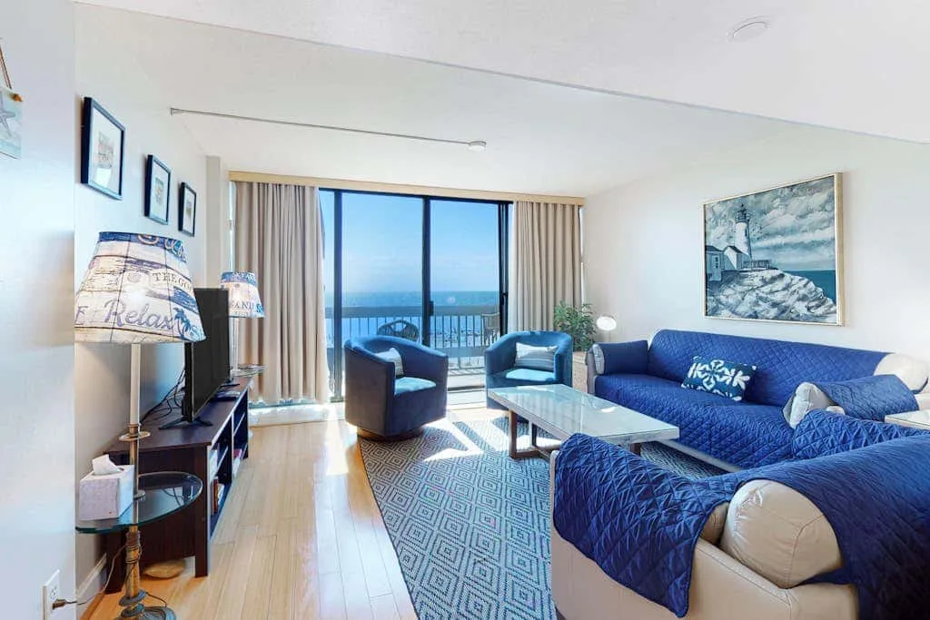 A bright living room with blue seating and a glass balcony door.