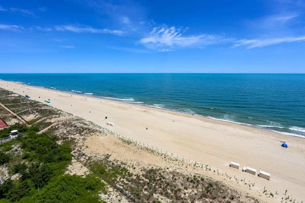 A wide sandy beach stretches along the blue ocean beneath a clear sky.