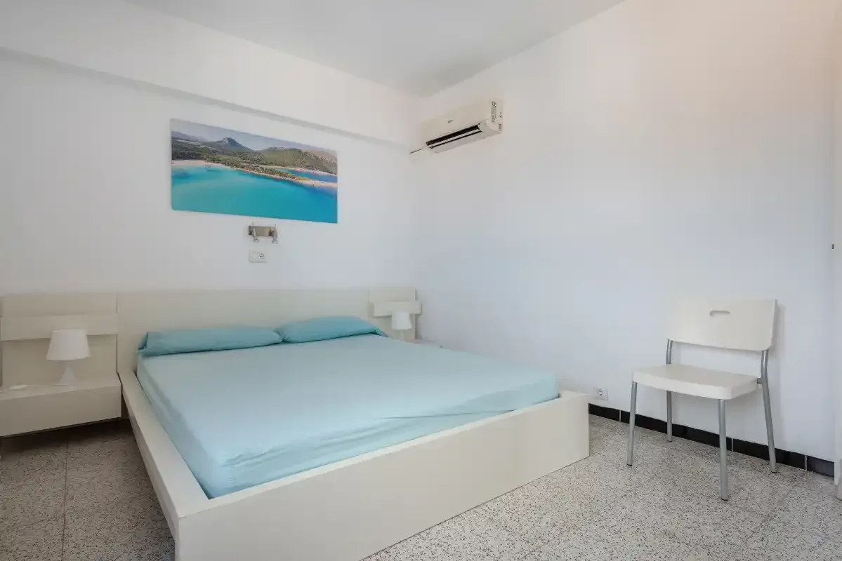 A bedroom with a bed, bedside tables, and a wall-mounted air conditioner.