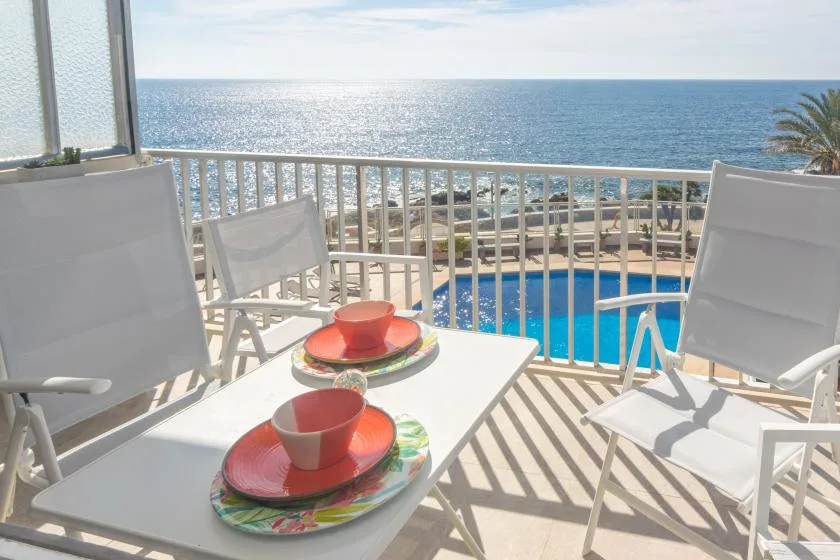 A balcony seating area overlooks a swimming pool and the ocean.