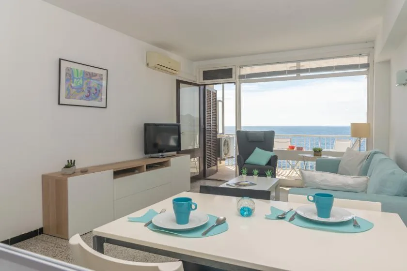 A bright living and dining area opens onto a balcony overlooking the sea.