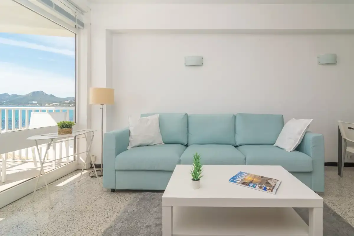 A bright living room with a pale blue sofa and a white coffee table.