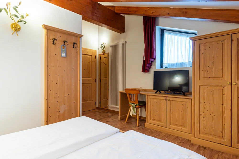 Habitación económica con muebles de madera, televisor y ventana.