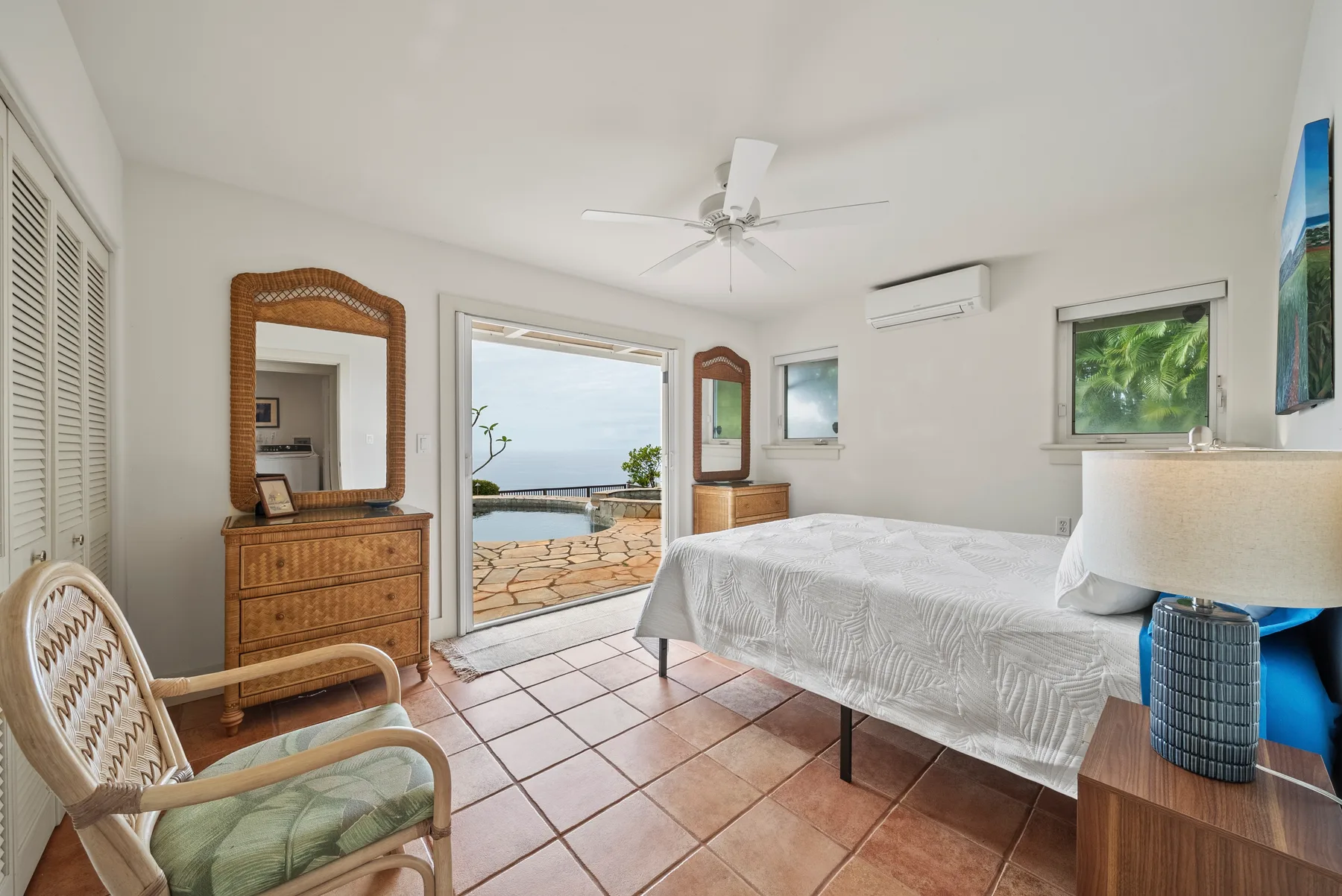 A bedroom with a bed, wicker seating, and an open doorway to a patio.