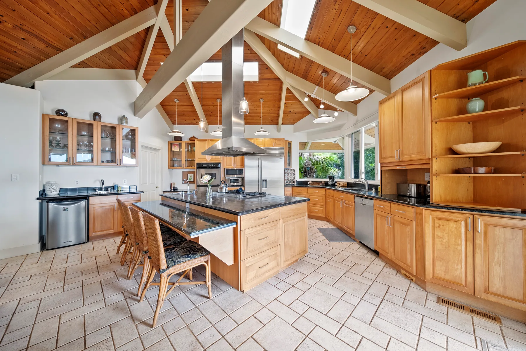A spacious kitchen with a central island and exposed wood ceiling beams.