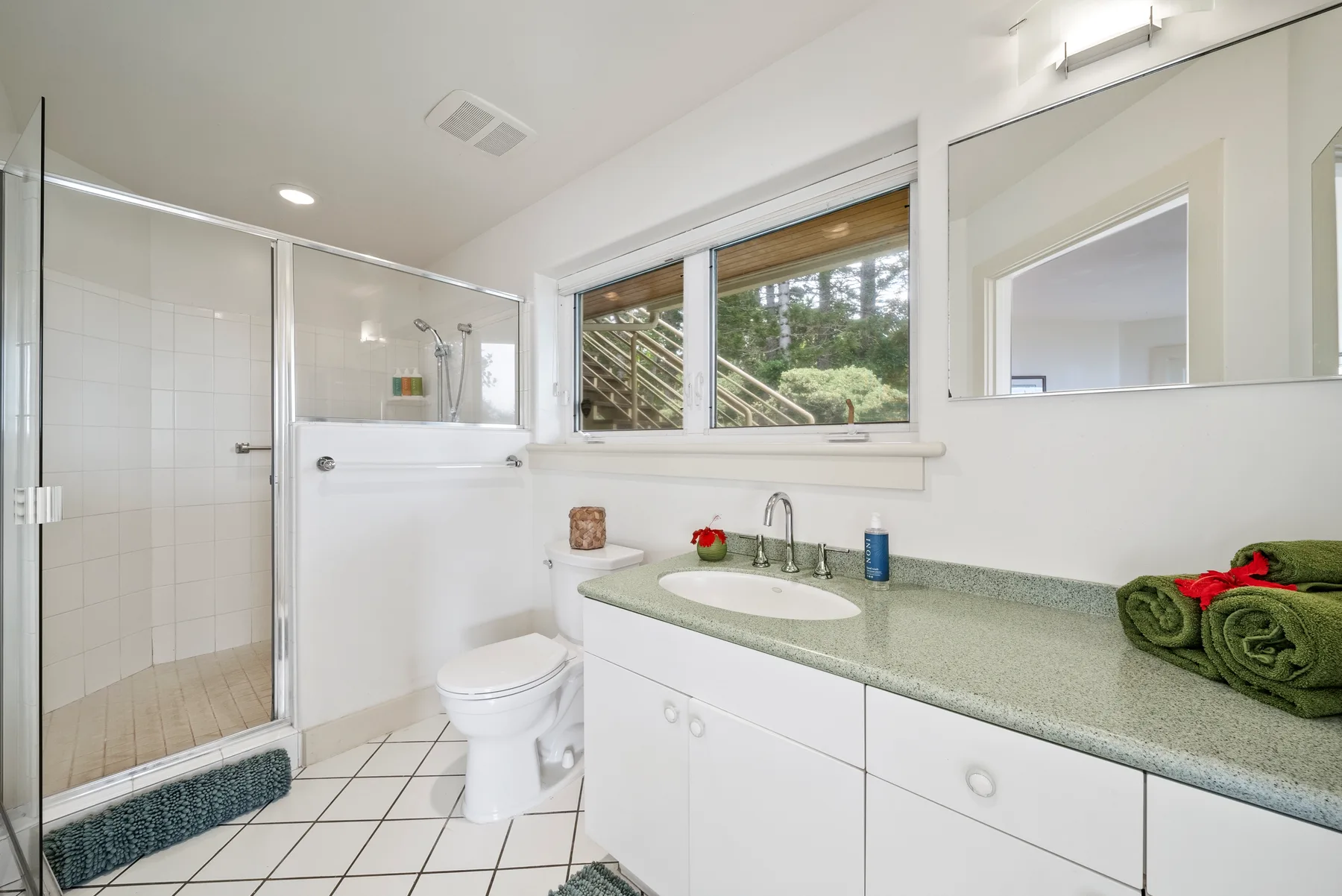 A bright bathroom with a glass shower, bathtub, and long vanity.