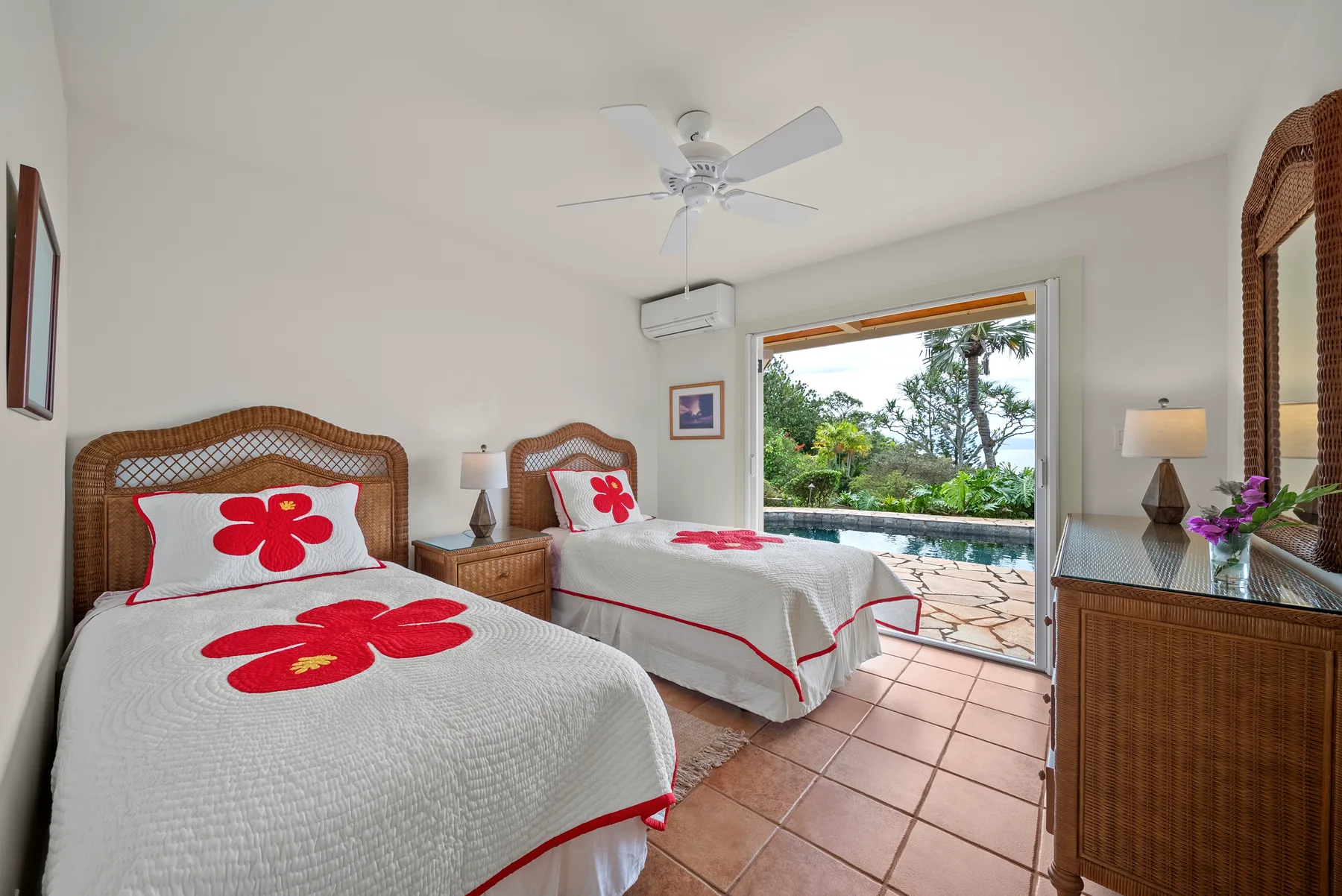 A bedroom with two beds, red floral bedding, and an open view to the patio.