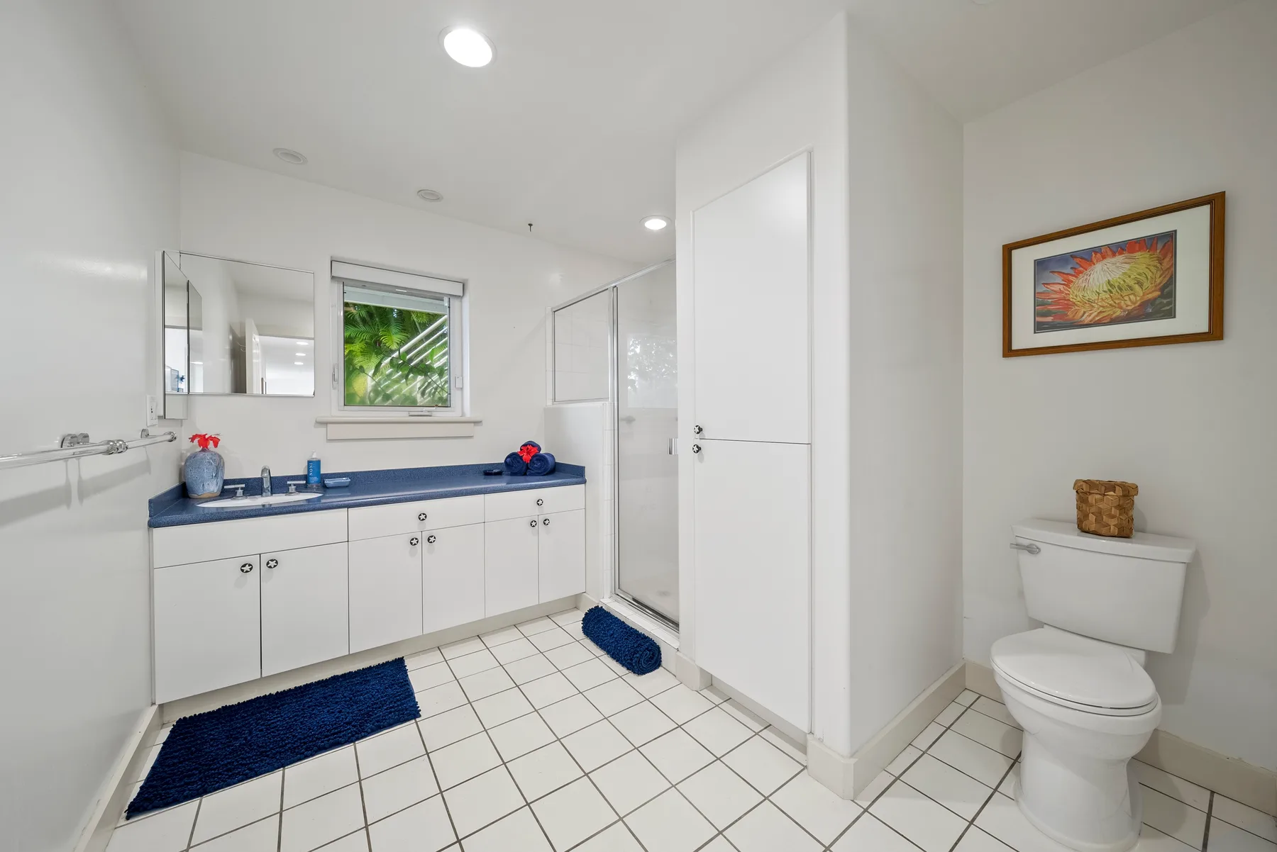 A bright bathroom with a long vanity, tiled floor, and toilet.