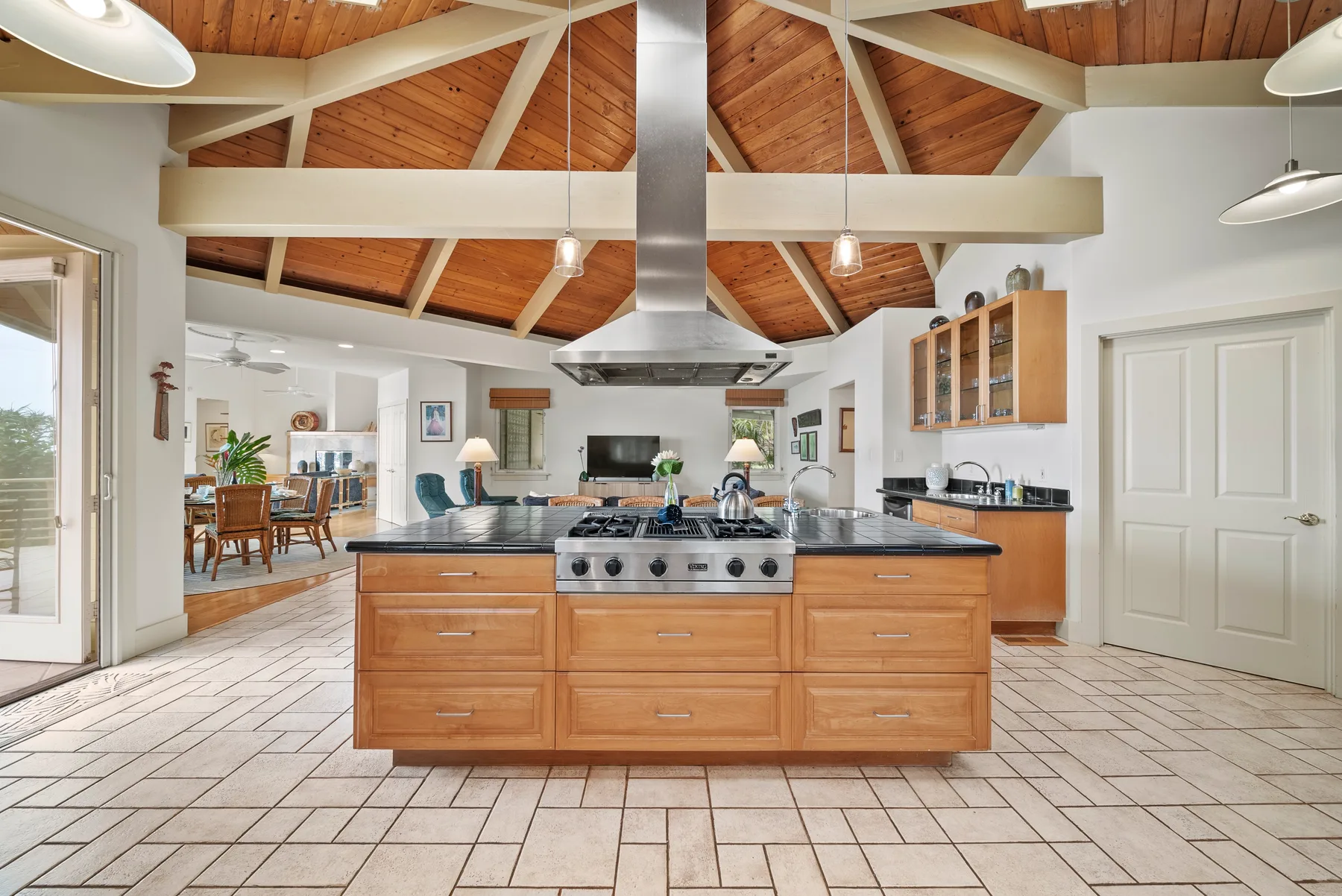 A spacious kitchen with a central island beneath a vaulted wooden ceiling.