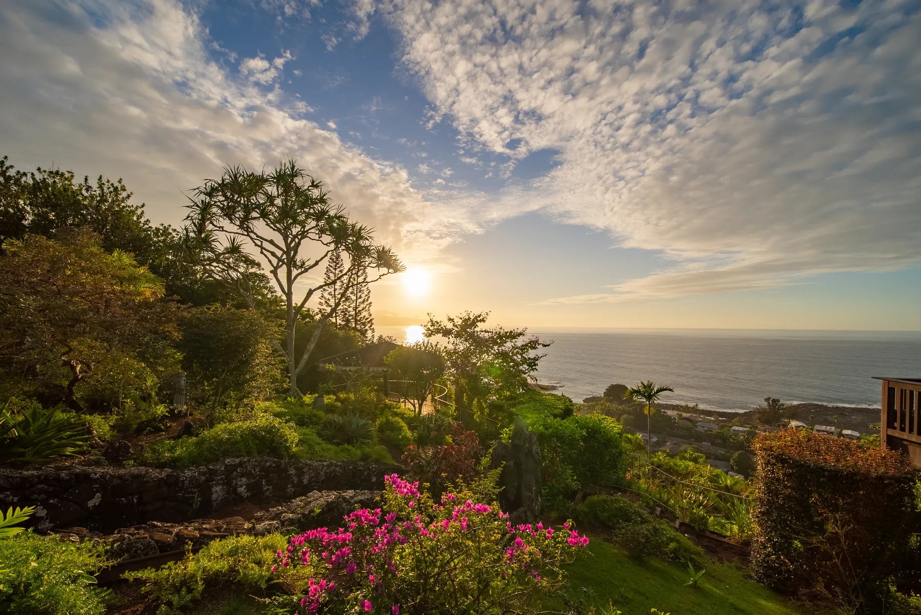 A landscaped garden overlooks the ocean beneath a cloudy sky.