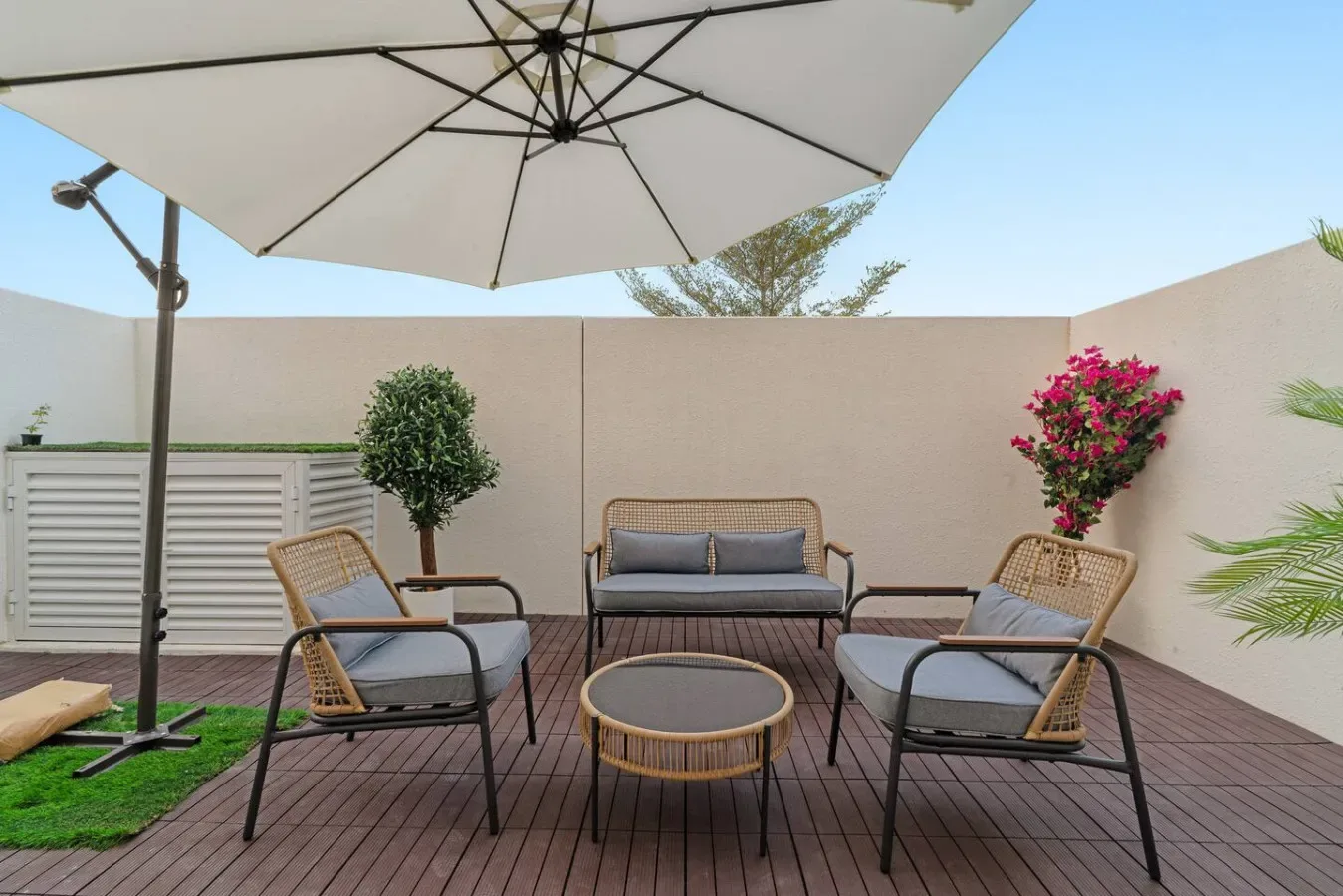 Un patio exterior con asientos, una mesa baja y una gran sombrilla.