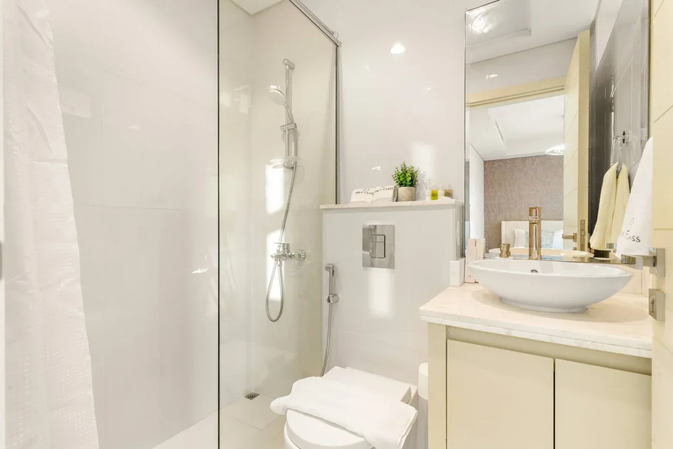 Un baño luminoso con ducha de vidrio, inodoro y lavabo.