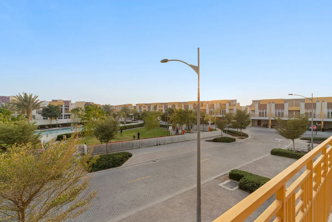 Un patio residencial pavimentado con zonas verdes ajardinadas y edificios alrededor.