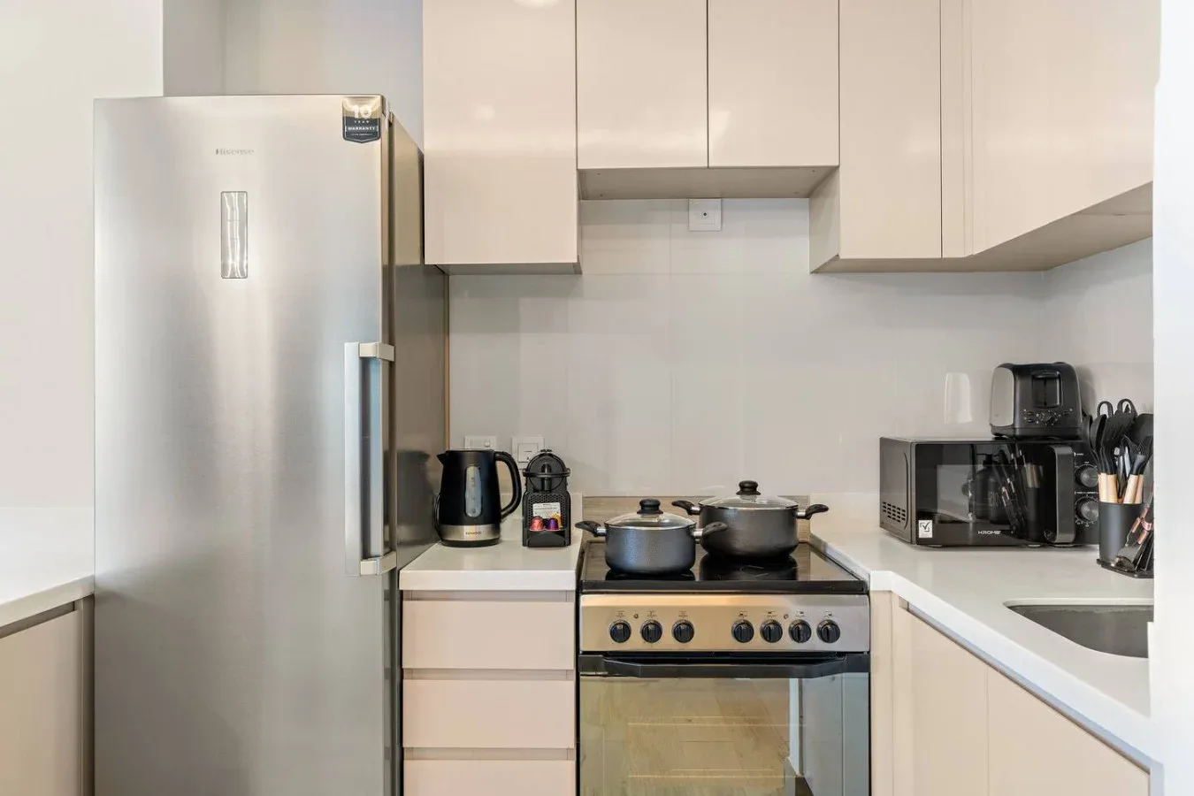 Una cocina moderna con refrigerador, estufa y electrodomésticos sobre la encimera.