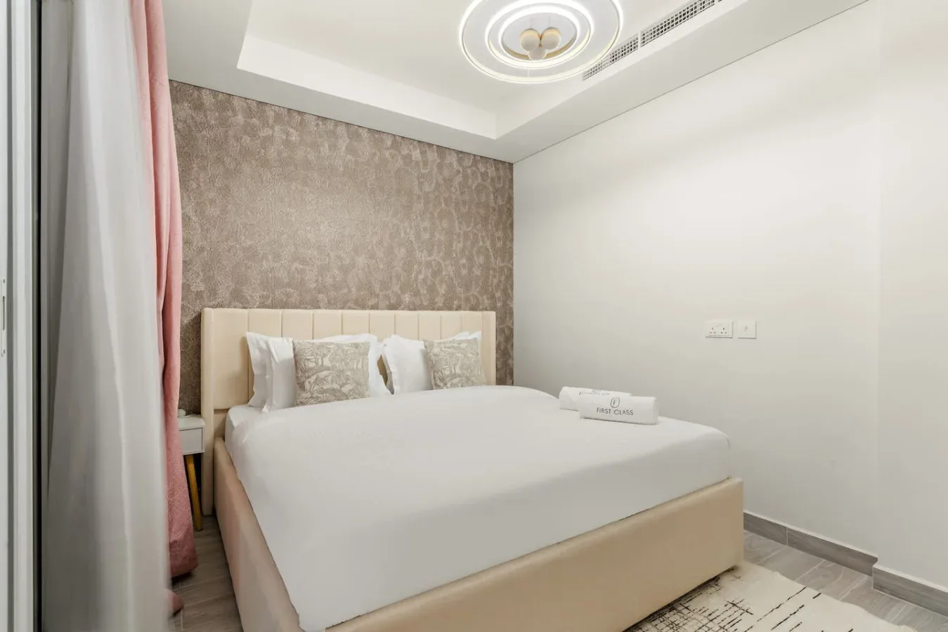 Un dormitorio con una cama bien arreglada y una pared decorativa estampada.