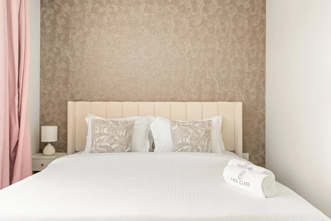 Un dormitorio con una cama bien tendida y almohadas estampadas.