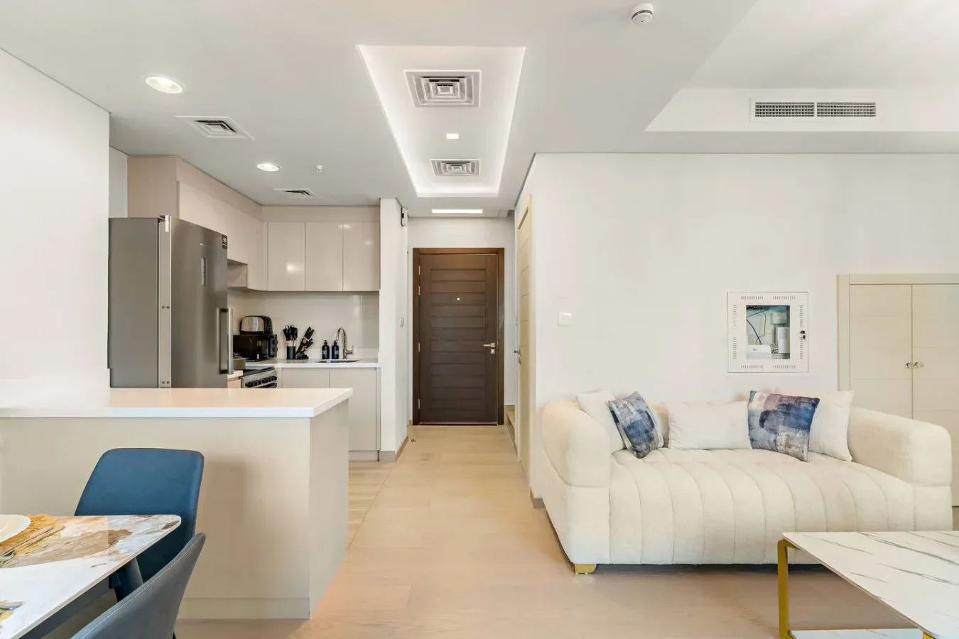 Una sala luminosa con un sofá blanco junto a una cocina abierta.