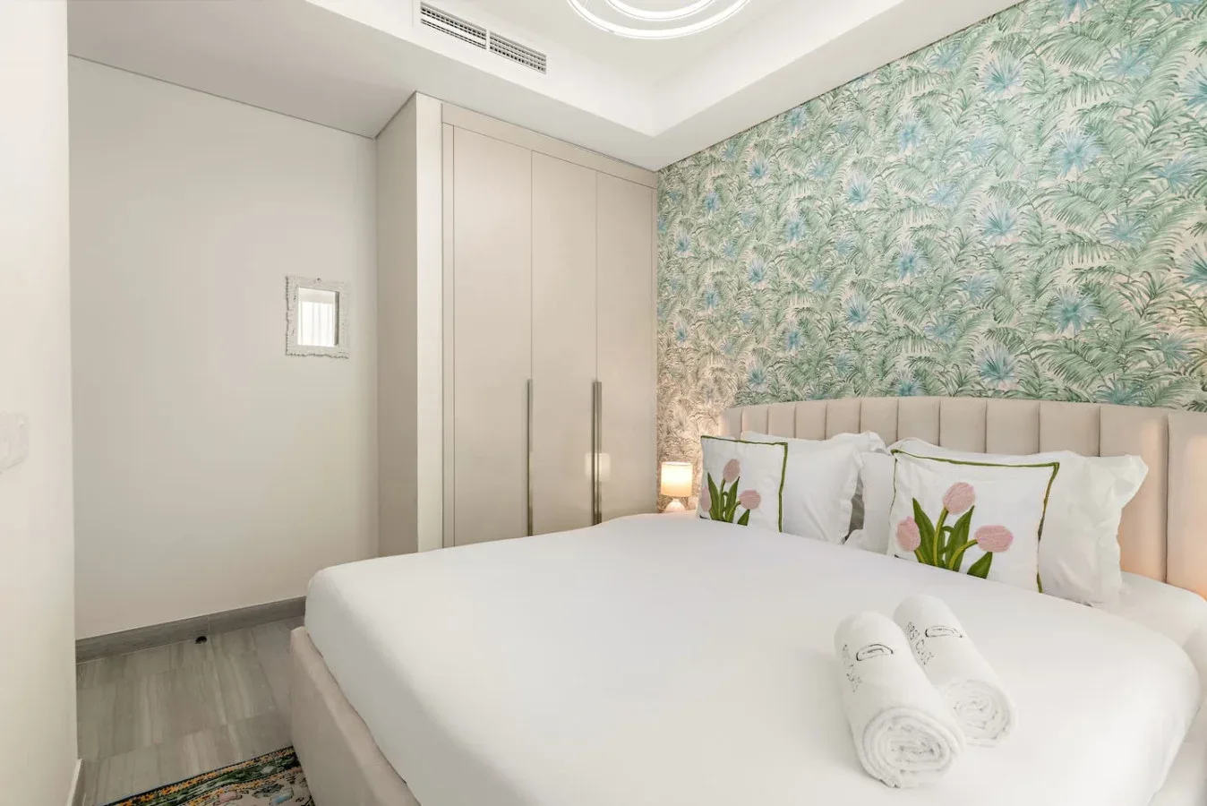 Un dormitorio con una cama bien tendida y papel tapiz estampado.