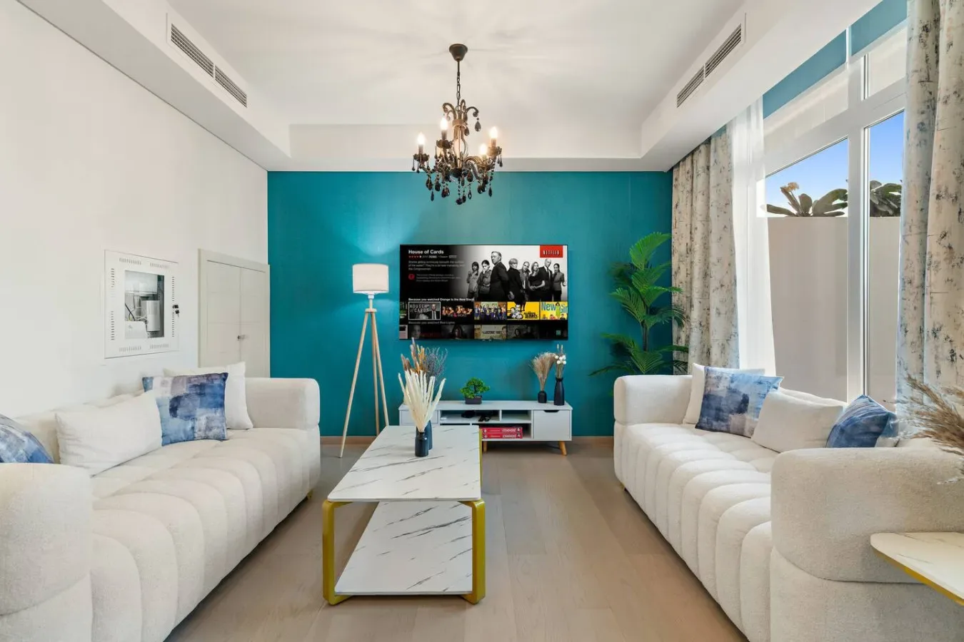 Una sala luminosa con asientos blancos, una mesa de centro y una pared turquesa.