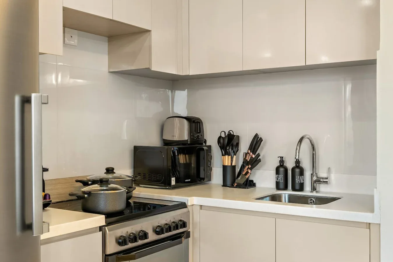 Una cocina moderna con armarios blancos, una encimera y una estufa.
