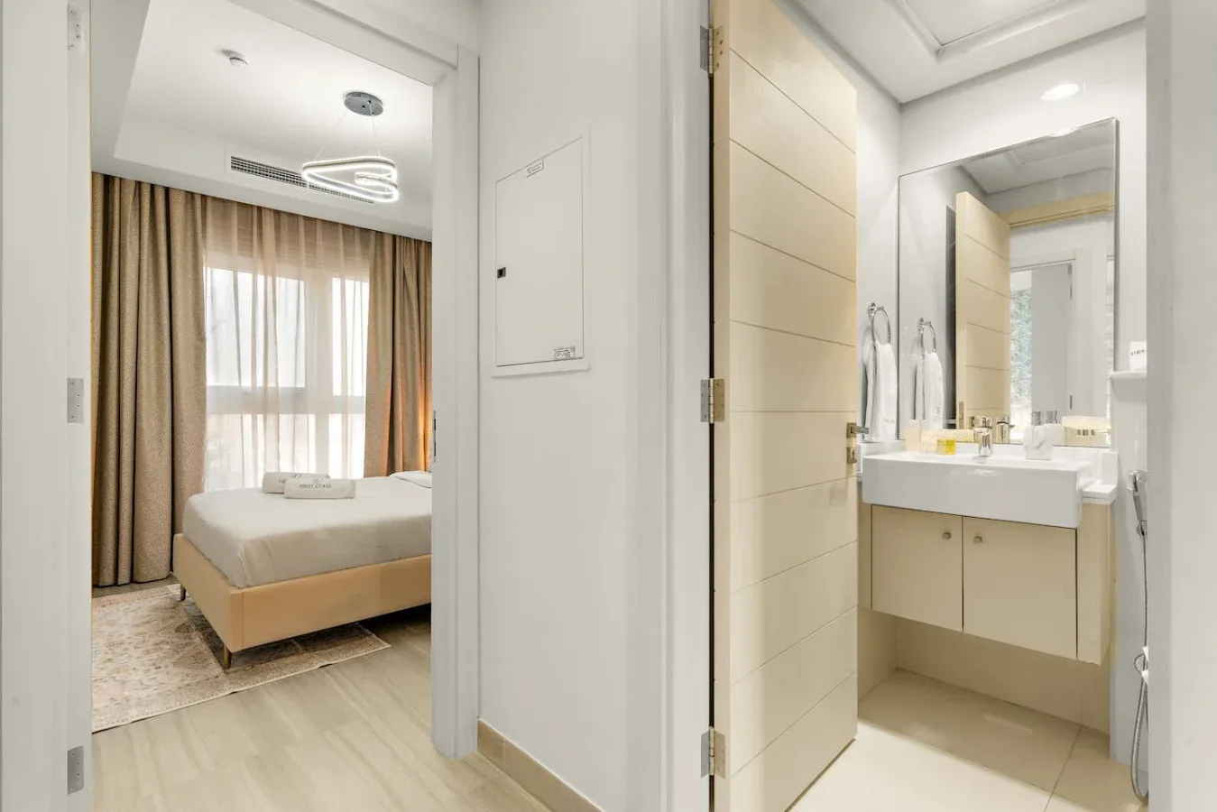 Se ven un dormitorio y un baño contiguo, con una cama y un lavabo.