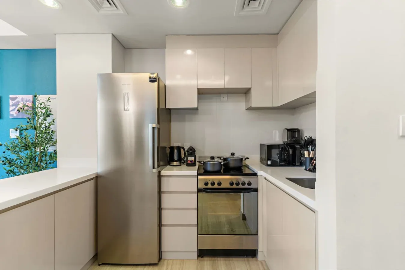 Una cocina luminosa con gabinetes blancos, electrodomésticos de acero inoxidable y una encimera.