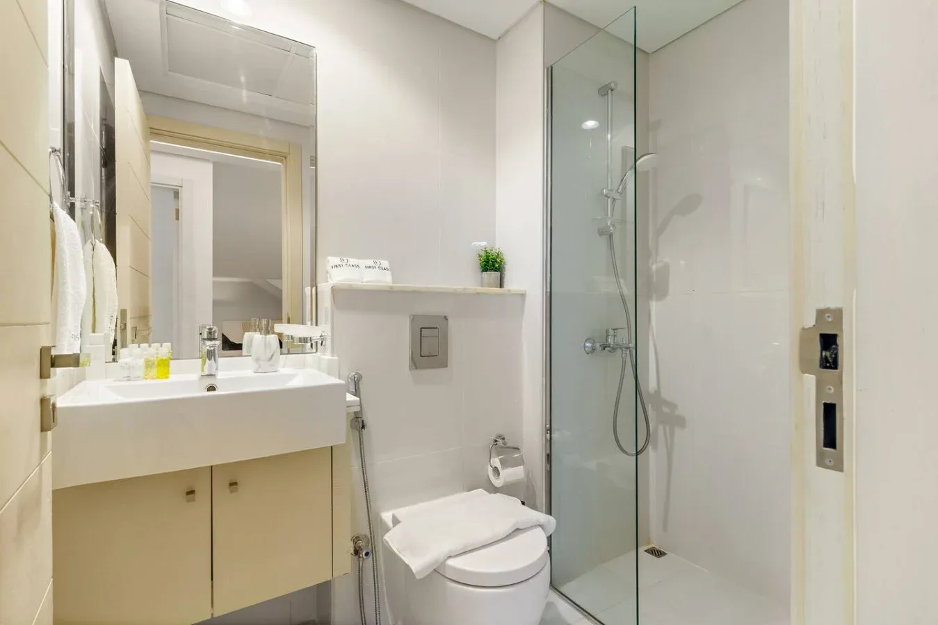 Un baño luminoso con lavabo, inodoro y ducha con mampara de vidrio.