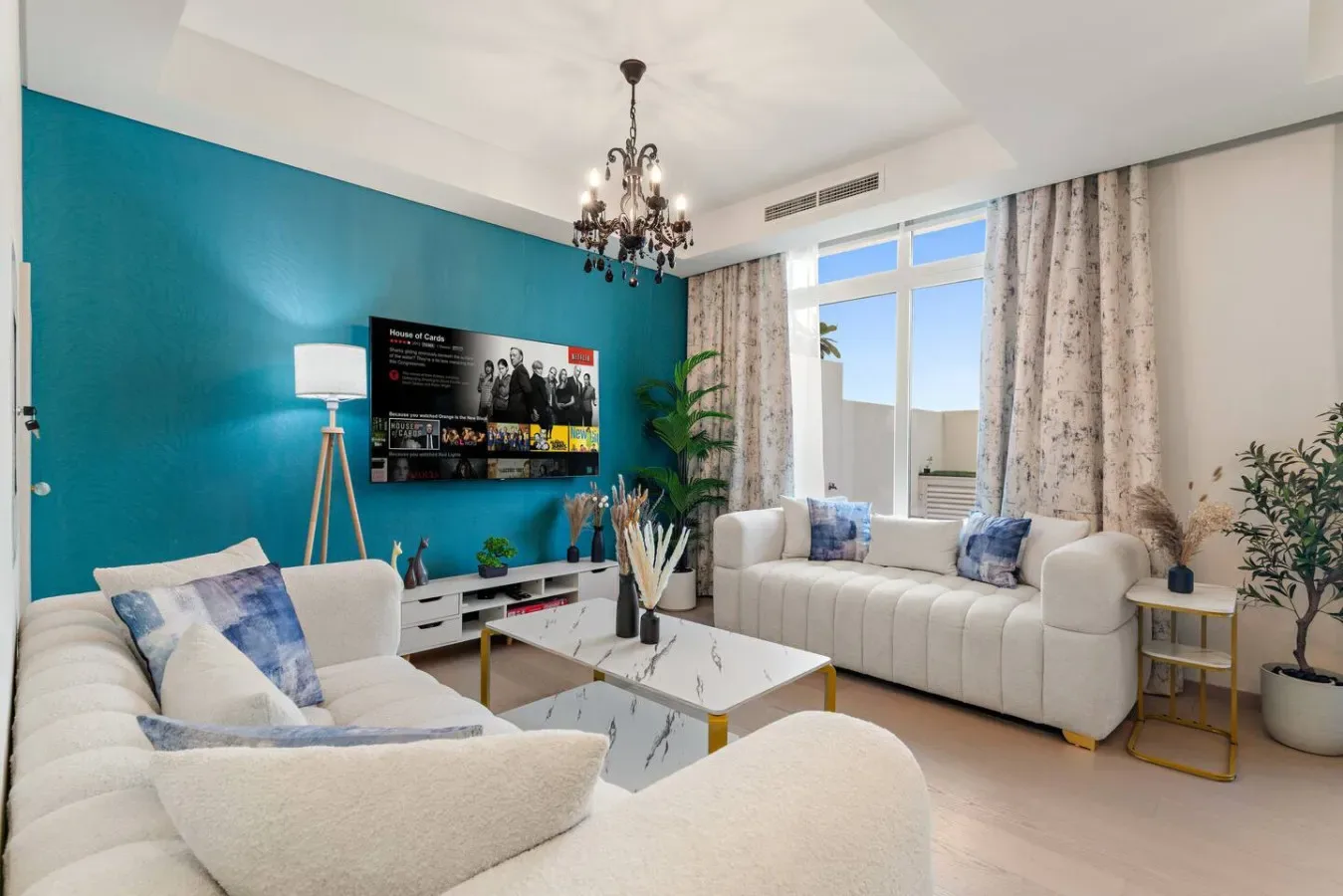 Una sala luminosa con asientos claros, un televisor y una ventana grande.