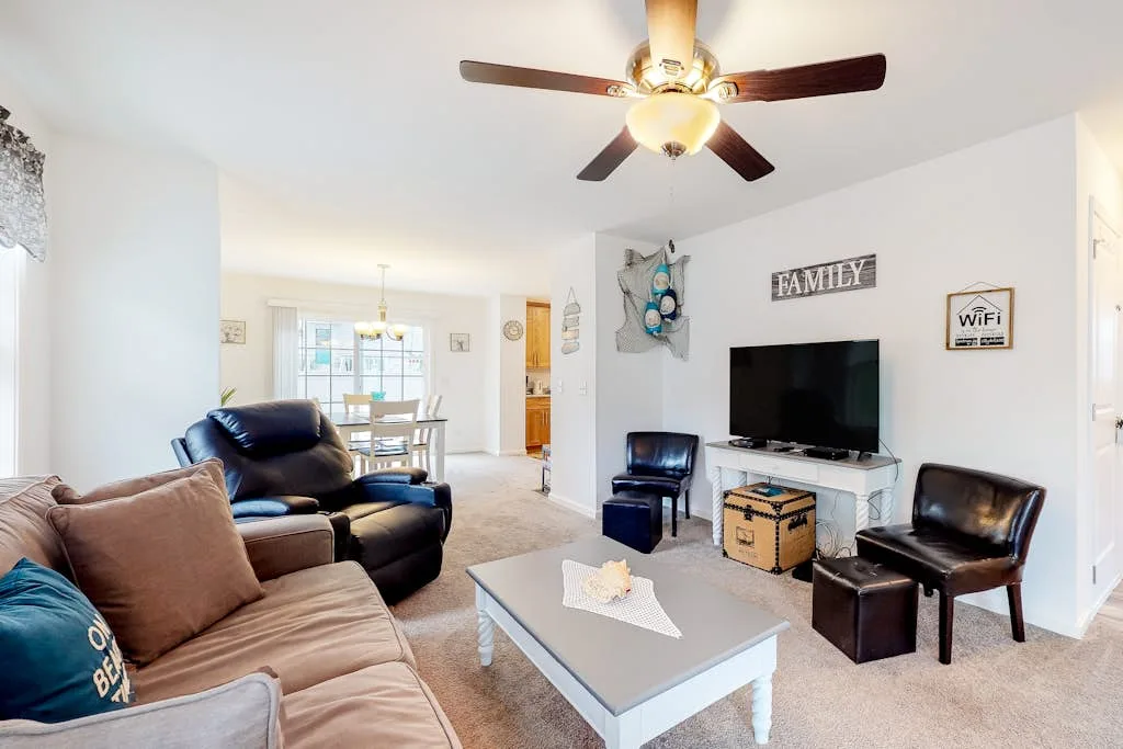 A living room with seating around a coffee table and television.