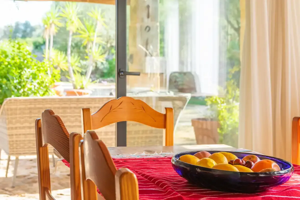 Un comedor con asientos de madera y un frutero sobre la mesa.