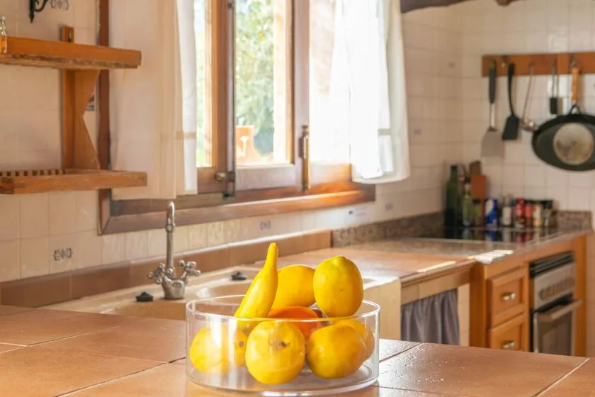 Una encimera de cocina con un recipiente de cítricos junto a una ventana iluminada.