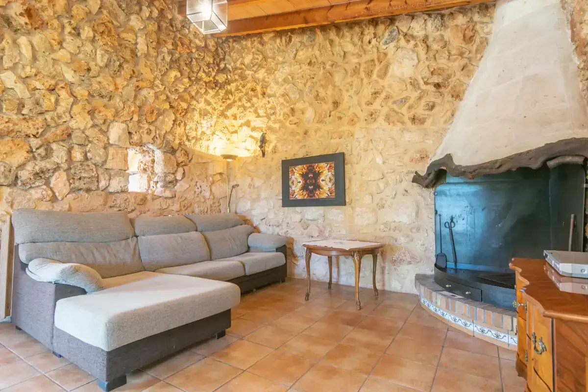 Una sala de estar rústica con asientos seccionales y una gran chimenea de piedra.