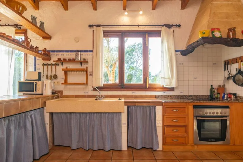 Una cocina rústica con armarios de madera y una ventana grande sobre el fregadero.