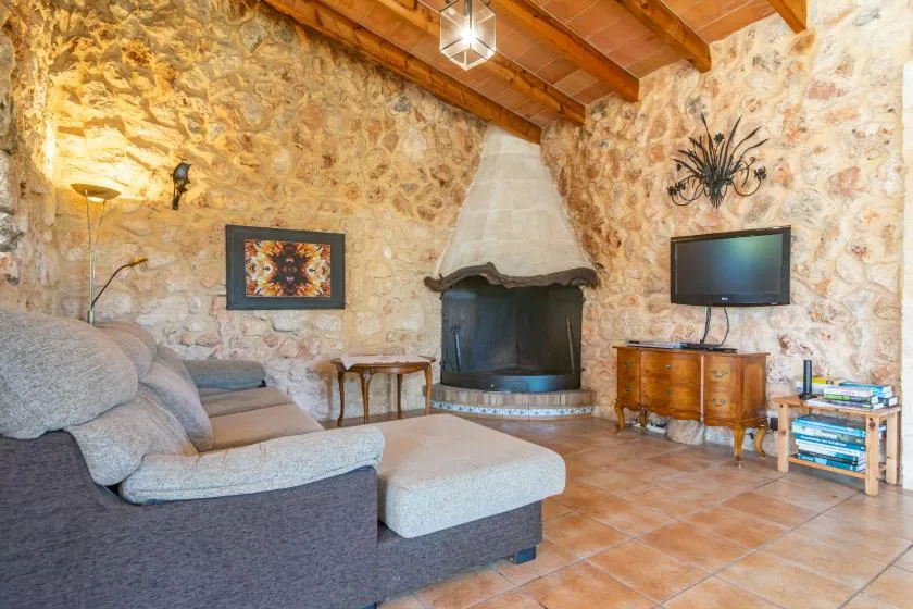Una sala rústica con asientos dispuestos alrededor de una chimenea de piedra.