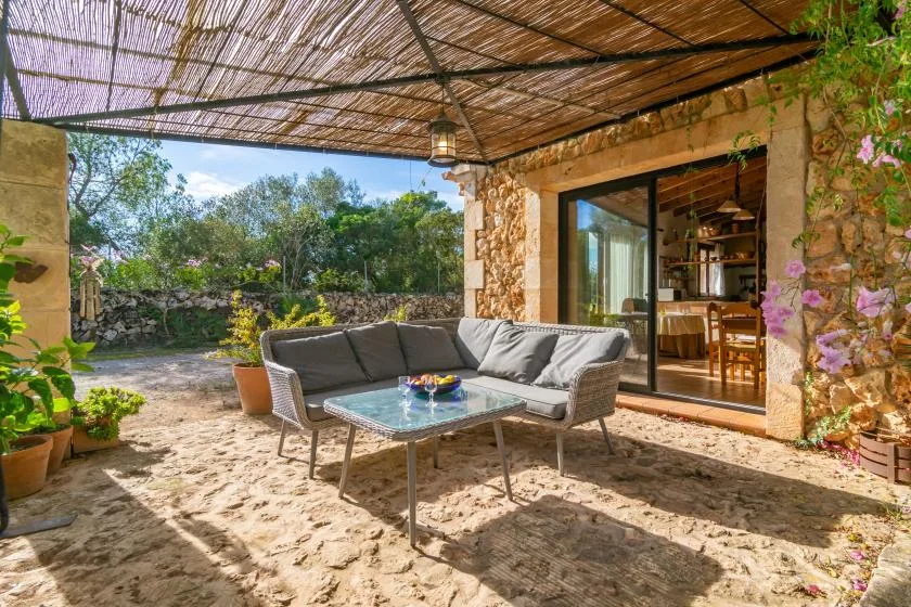 Un patio de piedra con asientos al aire libre bajo un toldo tejido.