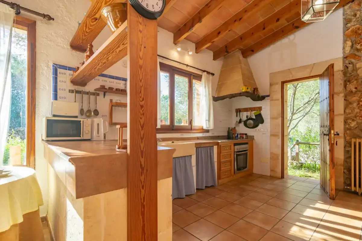 Una cocina rústica con armarios de madera y una puerta abierta al jardín.