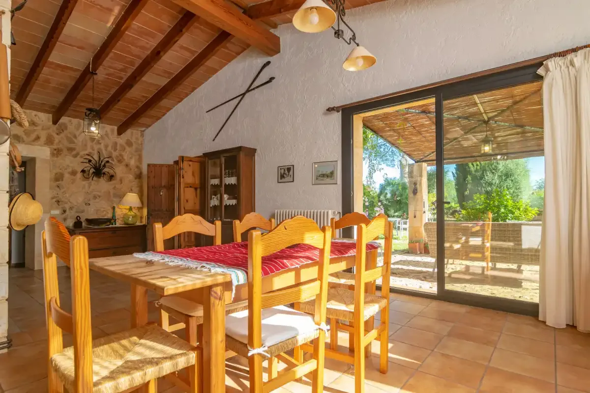 Comedor con mesa y sillas de madera junto a puertas correderas de cristal.