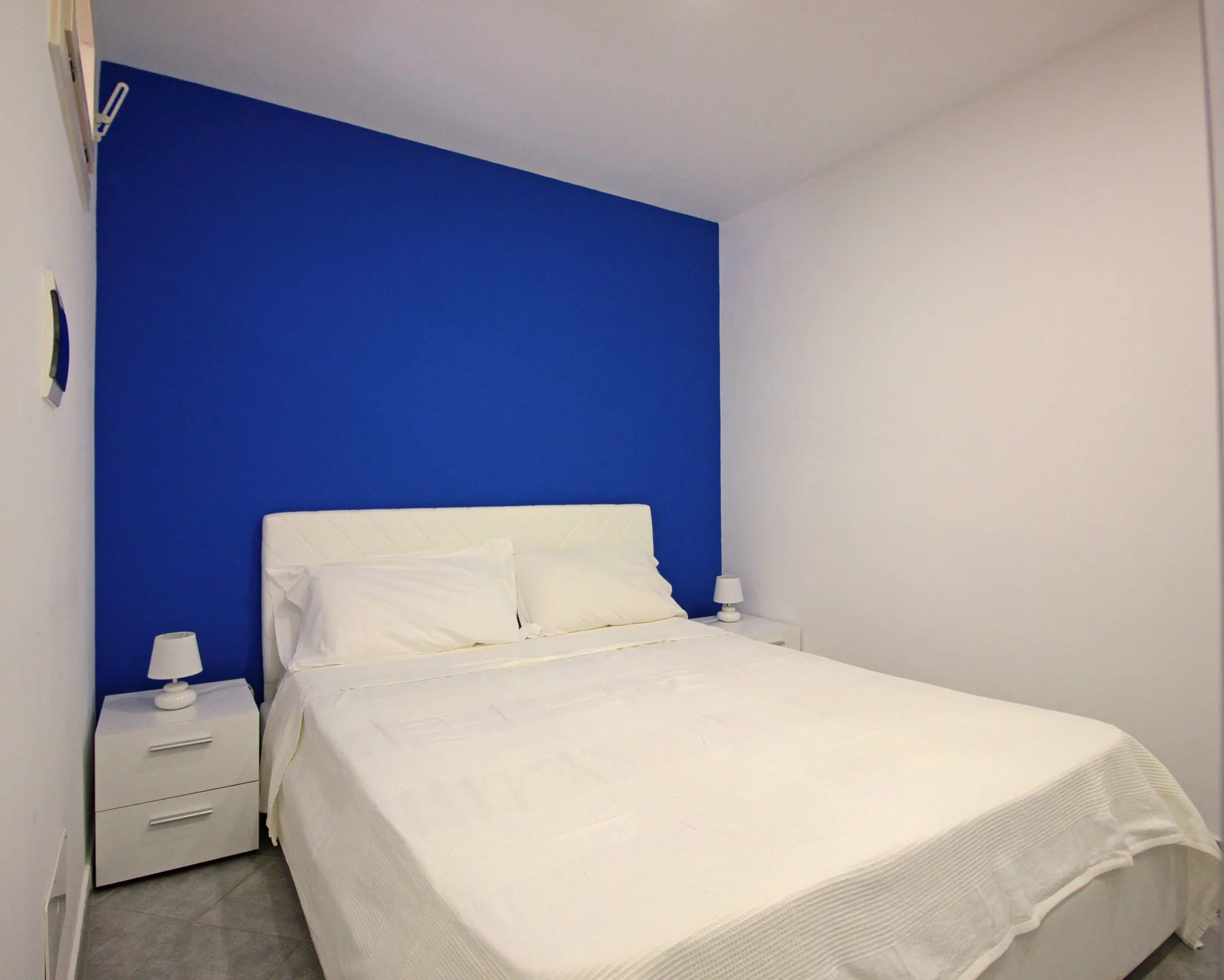 A bedroom with a neatly made bed against a blue accent wall.