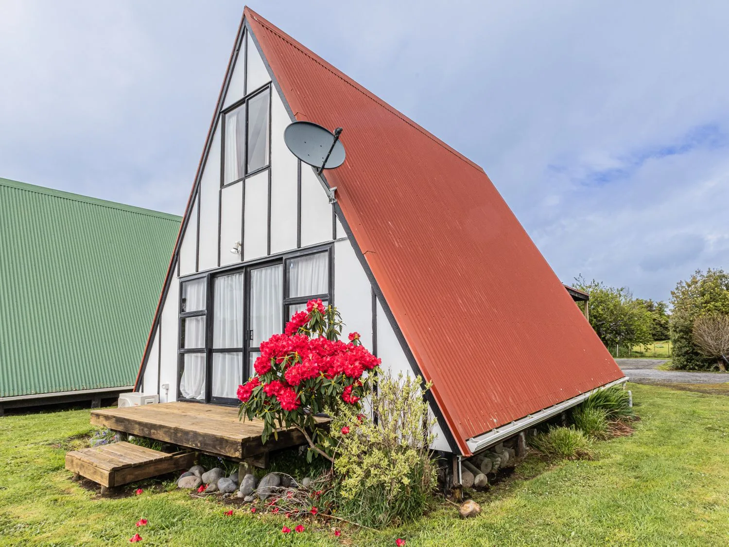 Una casa con techo rojo y flores en el jardín en Mountain View - Ohakune Holiday Home Ohakune