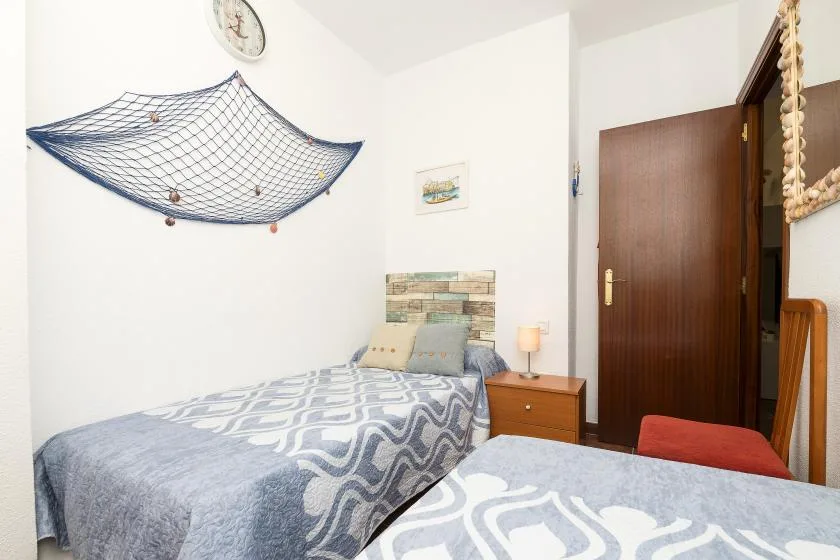 A bedroom with two beds, patterned bedding, and a wooden door.