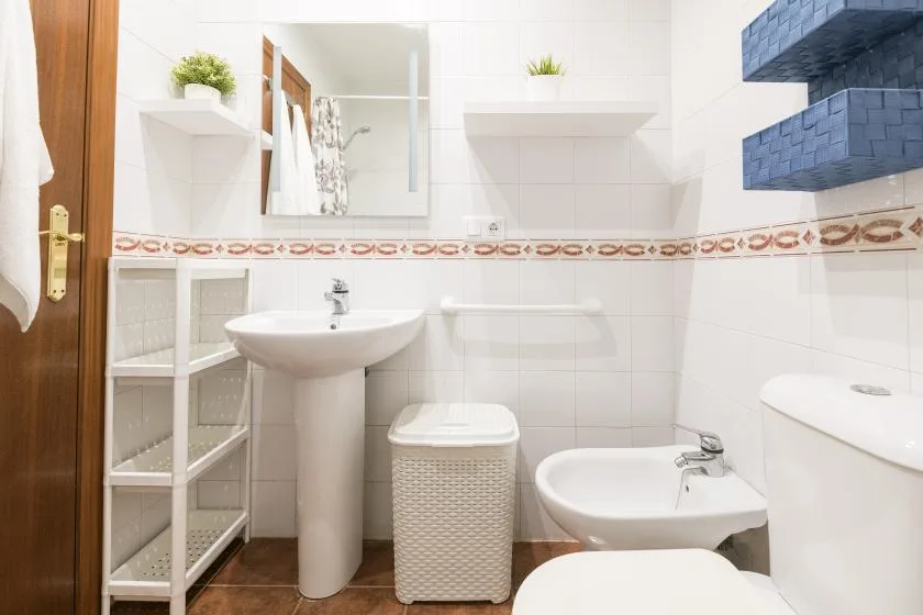 A tiled bathroom with a pedestal sink, bidet, and toilet.