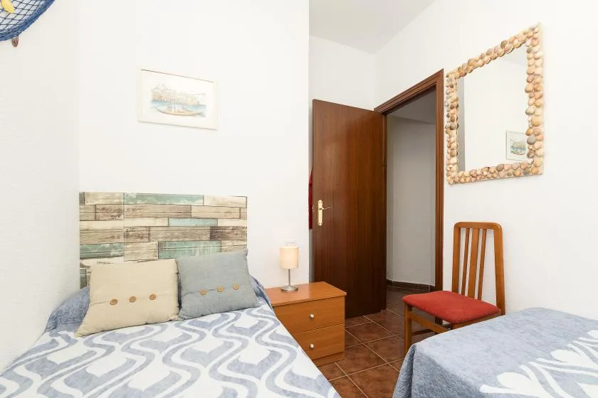 A bedroom with two beds, a wooden bedside table, and a mirror.