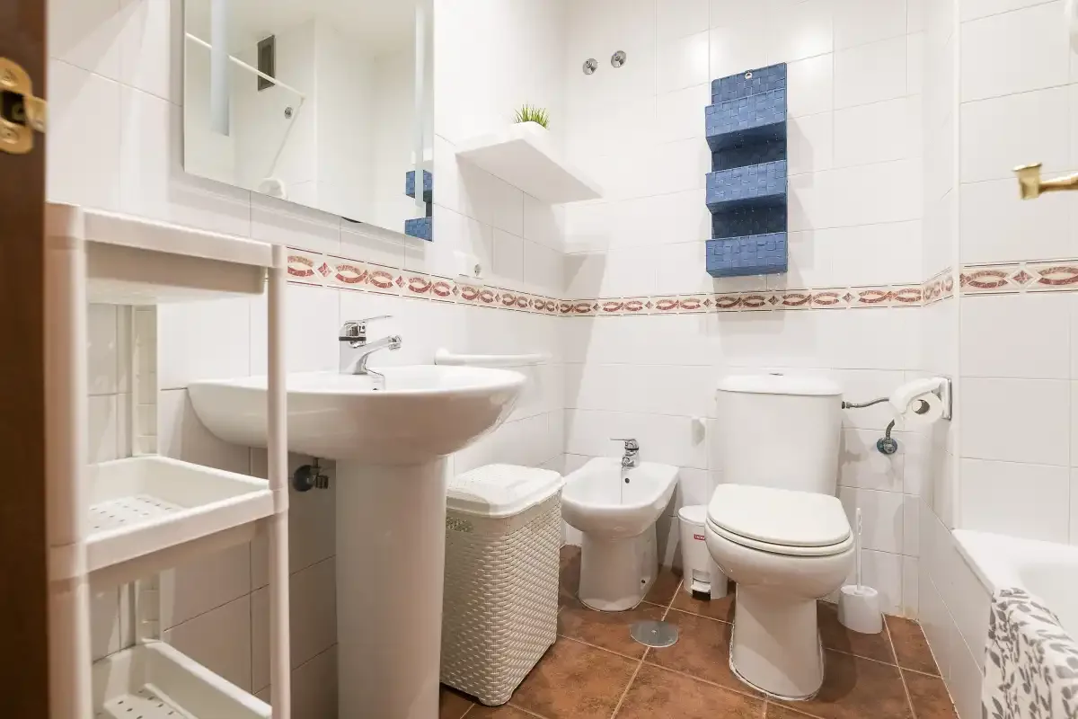 A tiled bathroom with a sink, toilet, bidet, and shower area.